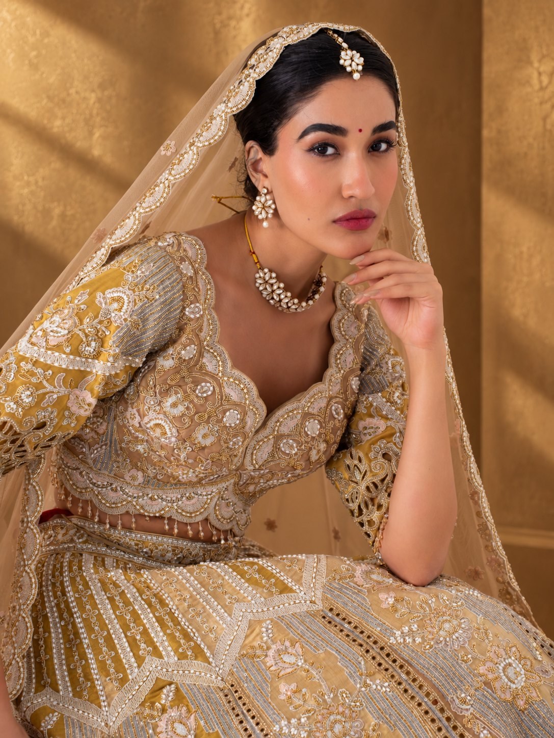 Close-up of the antique gold cutwork lehenga's scalloped sweetheart-neck blouse and zari embroidery
