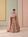 Model standing in a blush pink embroidered lehenga with a matching dupatta