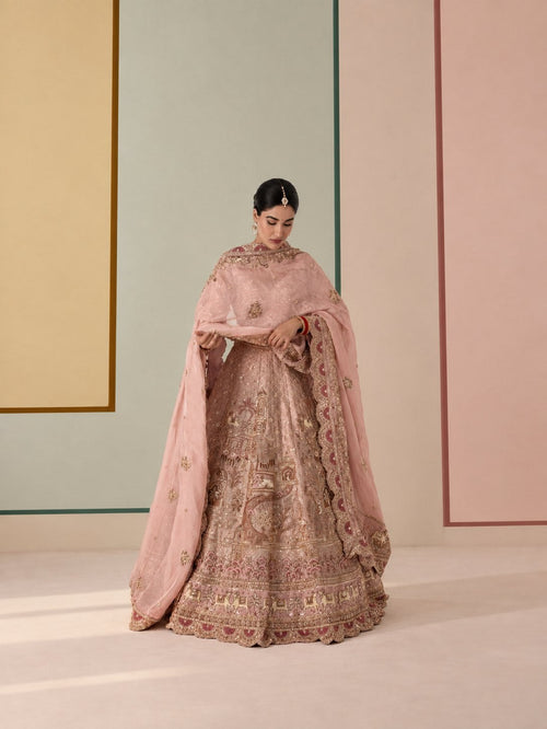 Model standing in a blush pink embroidered lehenga with a matching dupatta