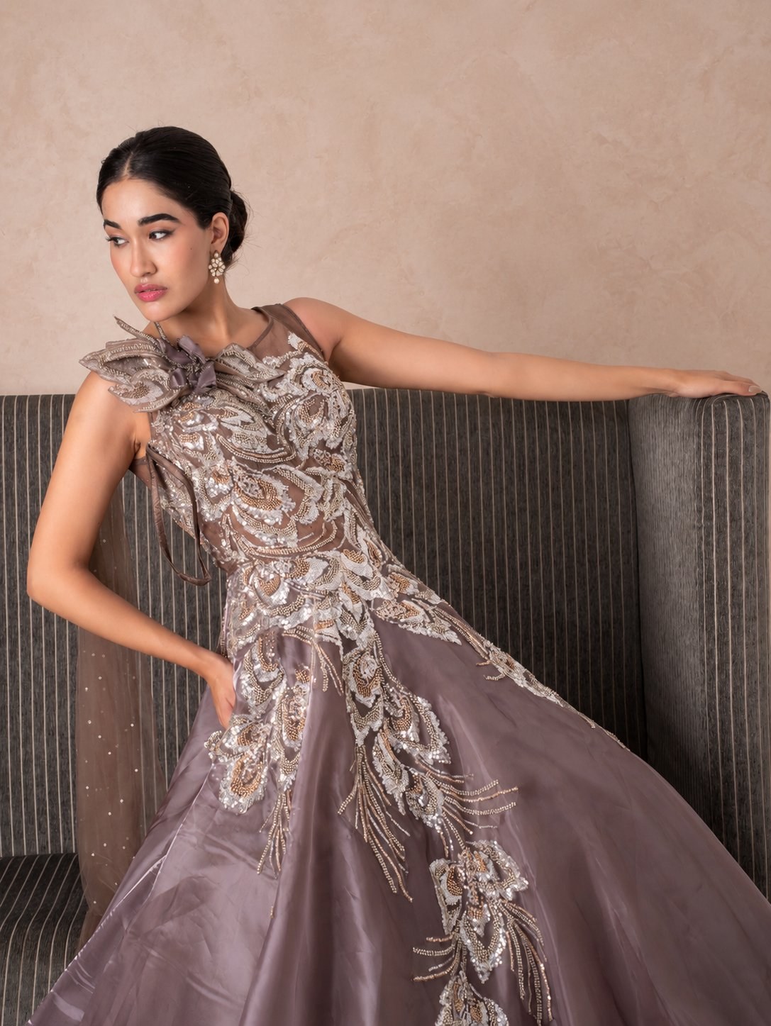 Model in a mauve gown with a sculpted floral shoulder and silver embellishment