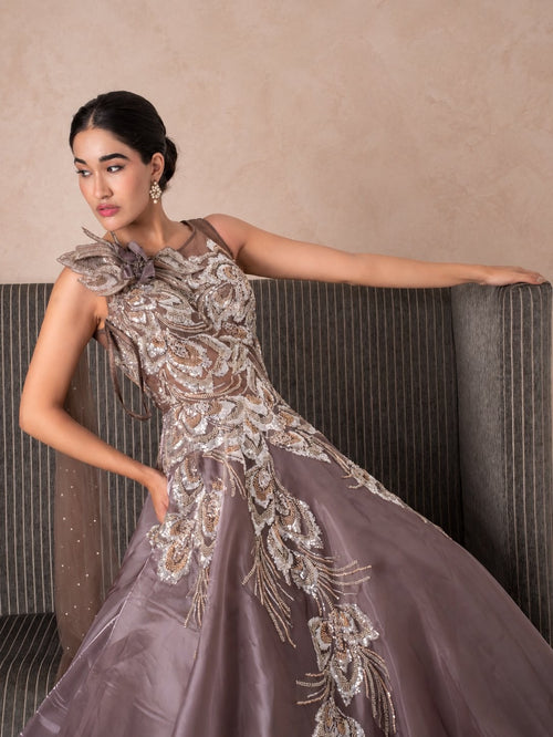 Model in a mauve gown with a sculpted floral shoulder and silver embellishment