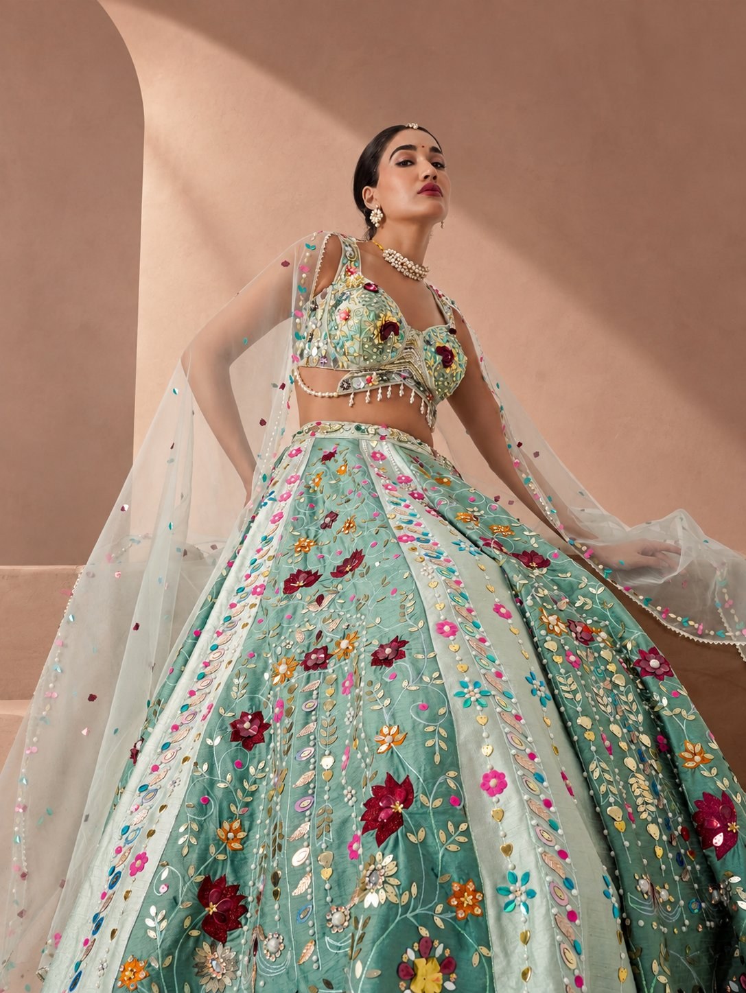 Model in a mint lehenga with multicolour floral appliqué and a sheer dupatta