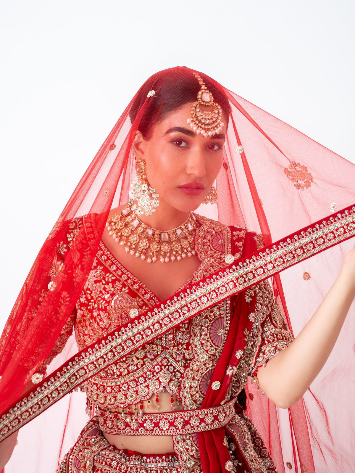 Red velvet bridal lehenga, with the dupatta worn as a veil